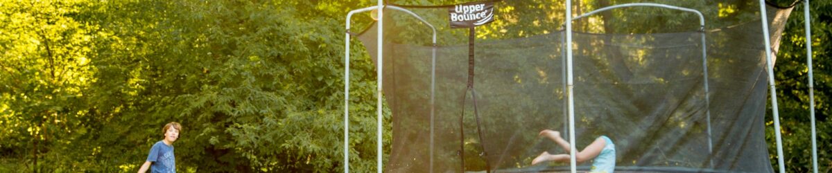 two children playing on a trampoline in a yard